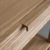 Tento odkládací stolek z masivního dubu kombinuje funkčnost s elegantním designem. Má dvě praktické zásuvky s charakteristickým drážkovaným čelem a minimalistickými úchyty, které dodávají moderní vzhled.