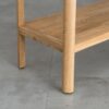 Tento odkládací stolek z masivního dubu kombinuje funkčnost s elegantním designem. Má dvě praktické zásuvky s charakteristickým drážkovaným čelem a minimalistickými úchyty, které dodávají moderní vzhled.