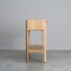 Tento odkládací stolek z masivního dubu kombinuje funkčnost s elegantním designem. Má dvě praktické zásuvky s charakteristickým drážkovaným čelem a minimalistickými úchyty, které dodávají moderní vzhled.