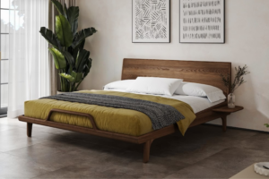 Nowoczesne łóżko z litego jesionu w eleganckim odcieniu orzecha z wysokim wezgłowiem, stylową drewnianą ramą i oryginalnym detalem dekoracyjnym w przedniej części. Delikatne krzywizny i lekka konstrukcja tworzą harmonijny mebel o ponadczasowym designie.